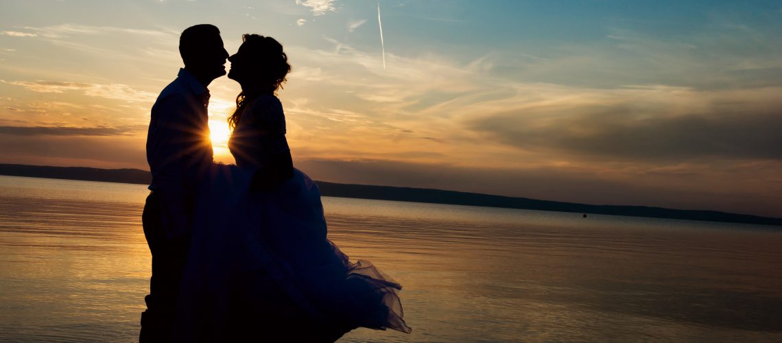 Beautiful young wedding couple standing on the beach